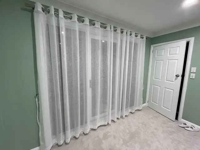 Freshly painted bedroom with white door and sheer curtains